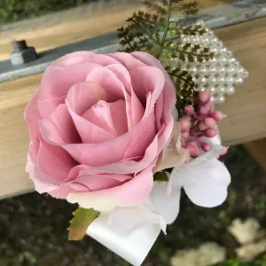 A wrist corsage featuring a dusky pink artificial silk rose